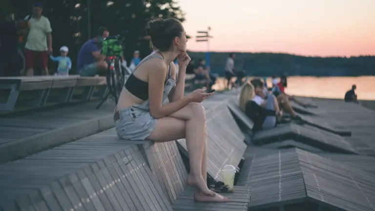 Kobieta odpoczywająca na drewnianych leżakach przy jeziorze podczas letniego popołudnia.