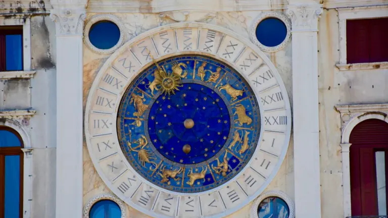 Zabytkowy zegar astronomiczny ze znakami zodiaku na fasadzie historycznego budynku w Europie.