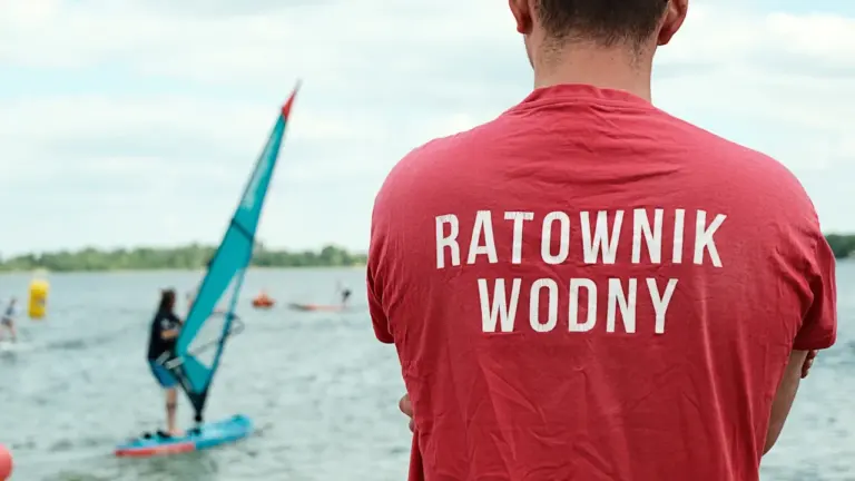 Ratownik wodny obserwujący jezioro podczas zawodów sportowych w Polsce w słoneczny dzień.
