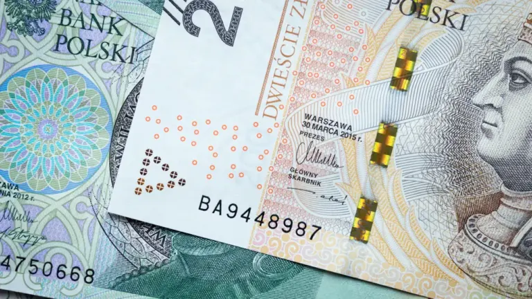 Zbliżenie na polskie banknoty złotowe leżące na zielonym tle, symbol polskiej waluty.