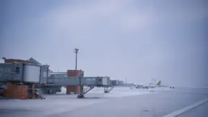 Rękawy lotniskowe i samolot na płycie lotniska podczas zimowej, mroźnej pogody w Polsce.
